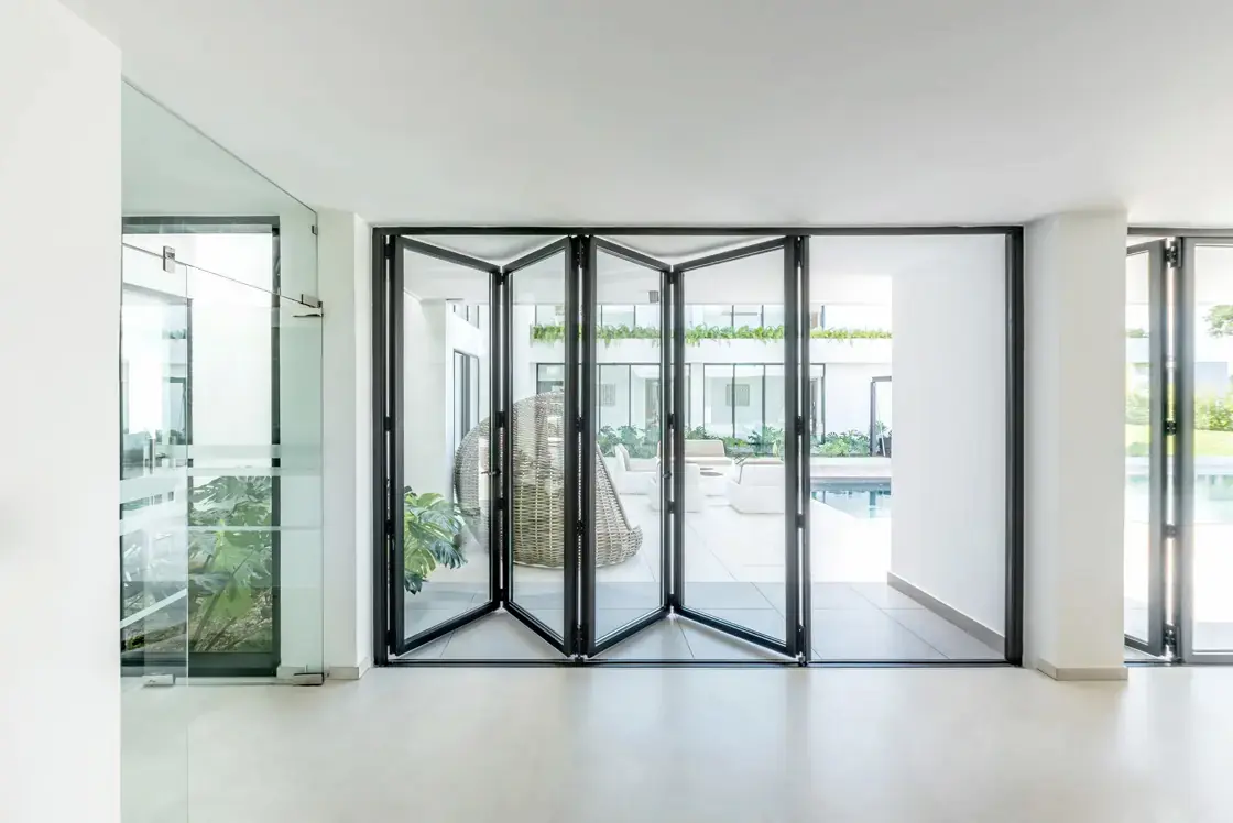Salon lumineux avec porte pliante vitrée ouverte.