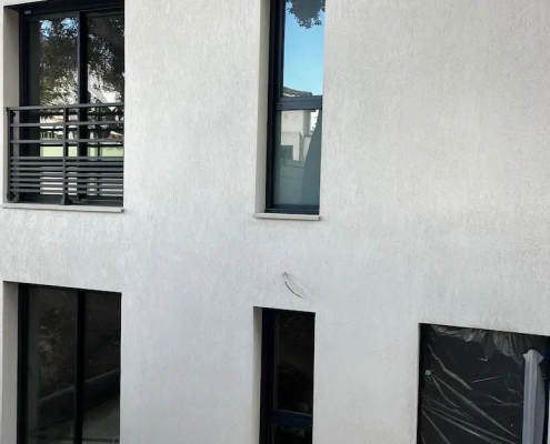 Façade moderne avec fenêtres et porte sombres.