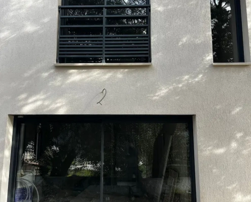 Façade avec fenêtres modernes et reflet d'arbres.