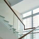 Escalier moderne en verre près de grandes fenêtres.